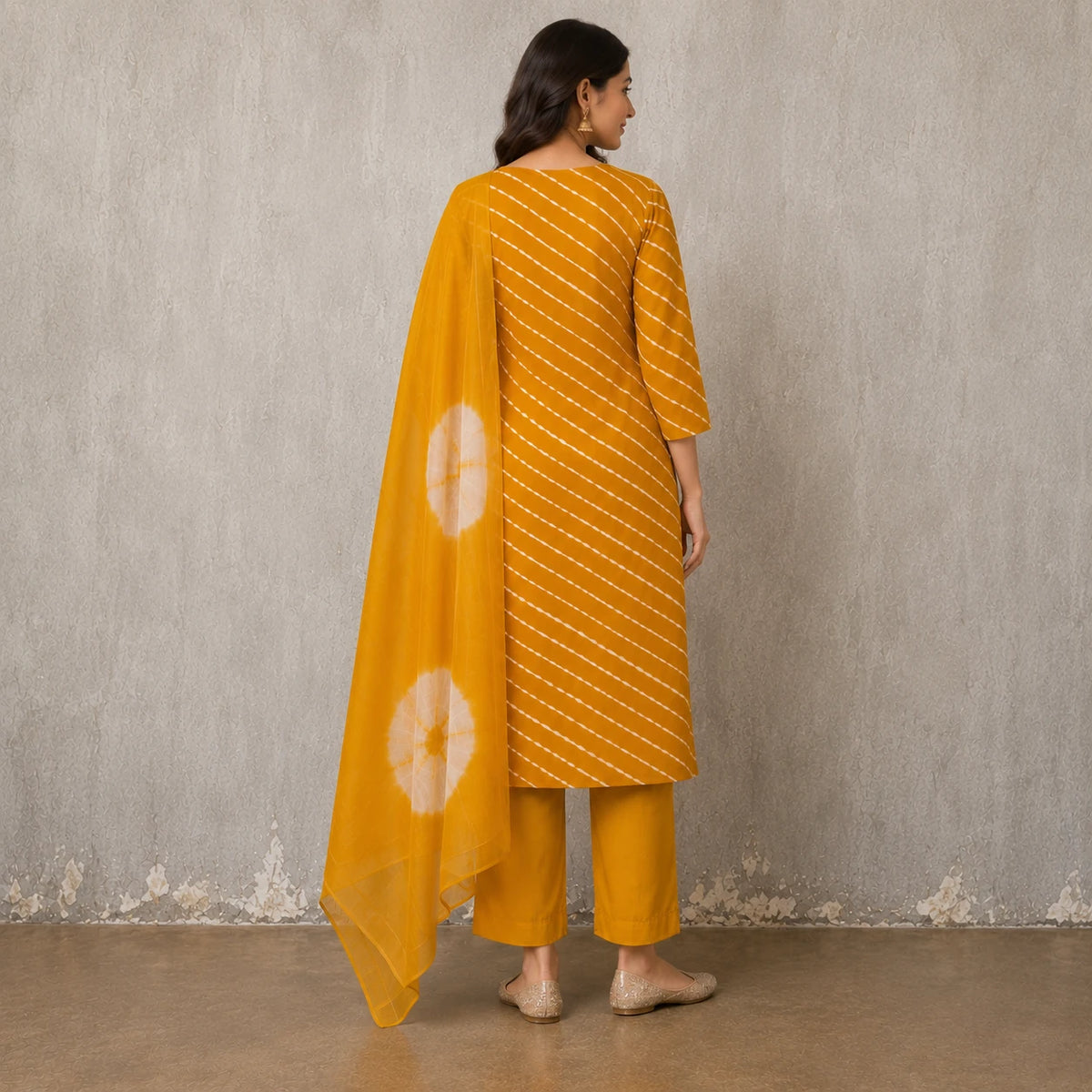 Woman wearing a mustard yellow Leheriya-inspired stripe kurta pant set with a tie-dye dupatta