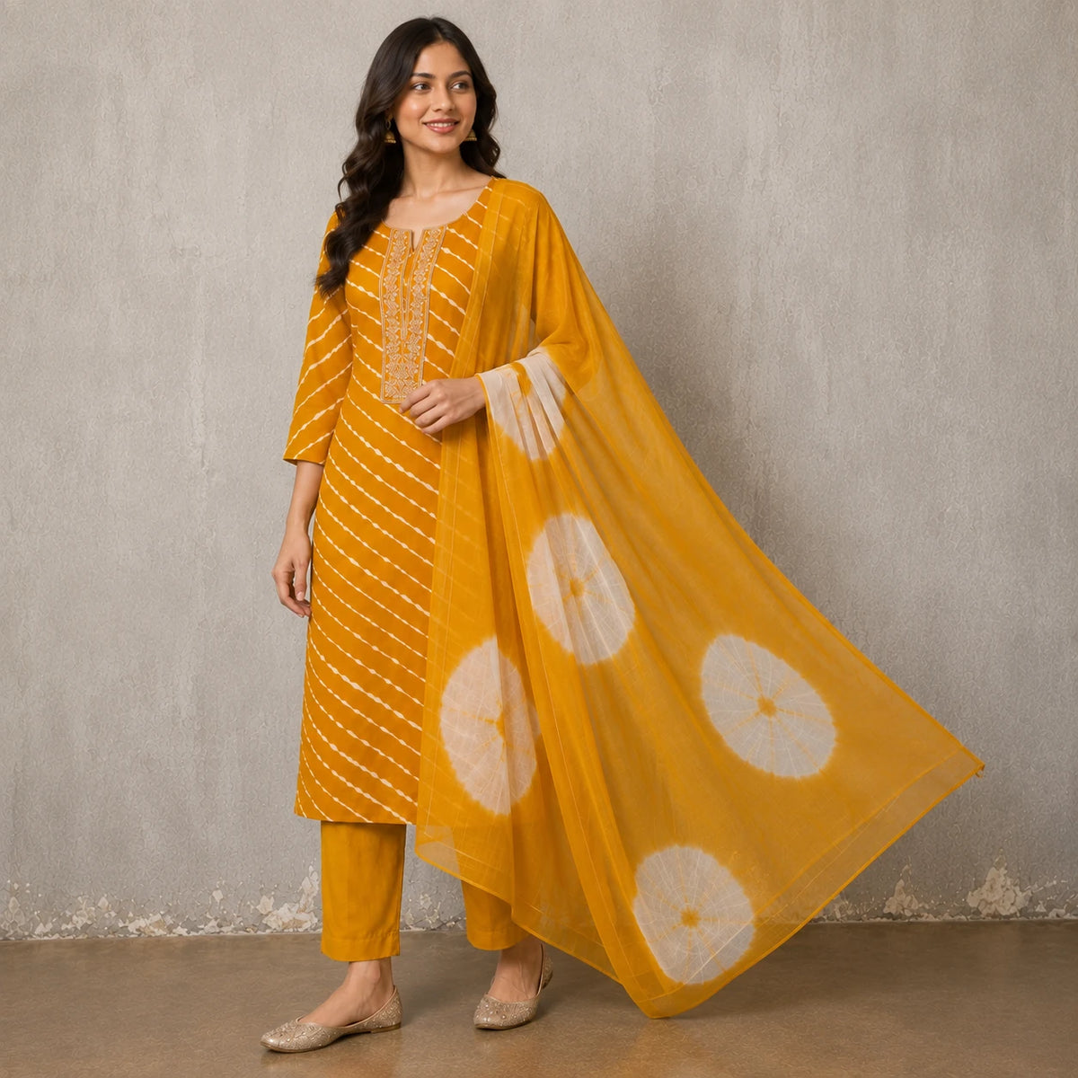 Woman wearing a mustard yellow Leheriya-inspired stripe kurta pant set with a tie-dye dupatta