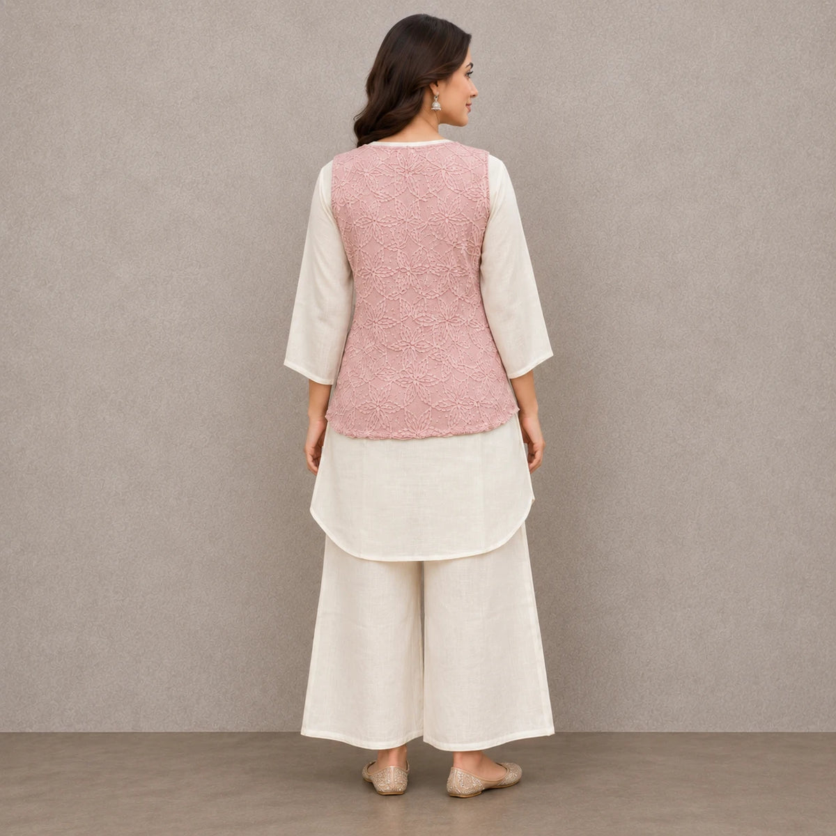 Woman wearing a blush pink floral embroidered peplum kurta with ivory inner top and wide-leg palazzo pants