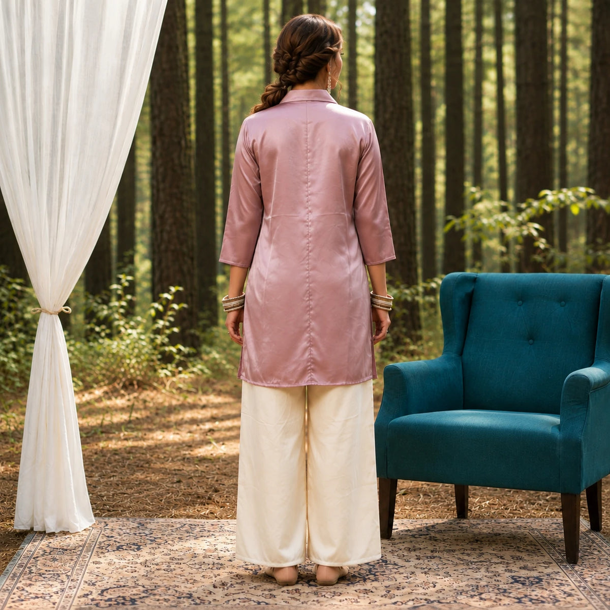 Woman wearing a dusty rose long shirt with decorative front embellishment and ivory wide-leg pants